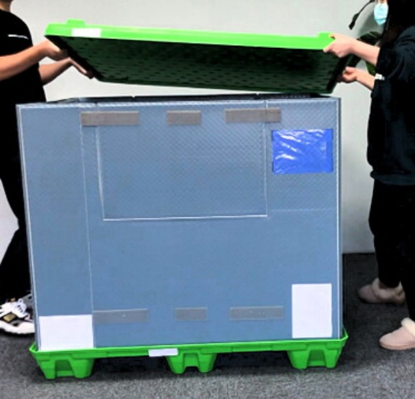 Two people placing the green lid onto the assembled sleeve box.